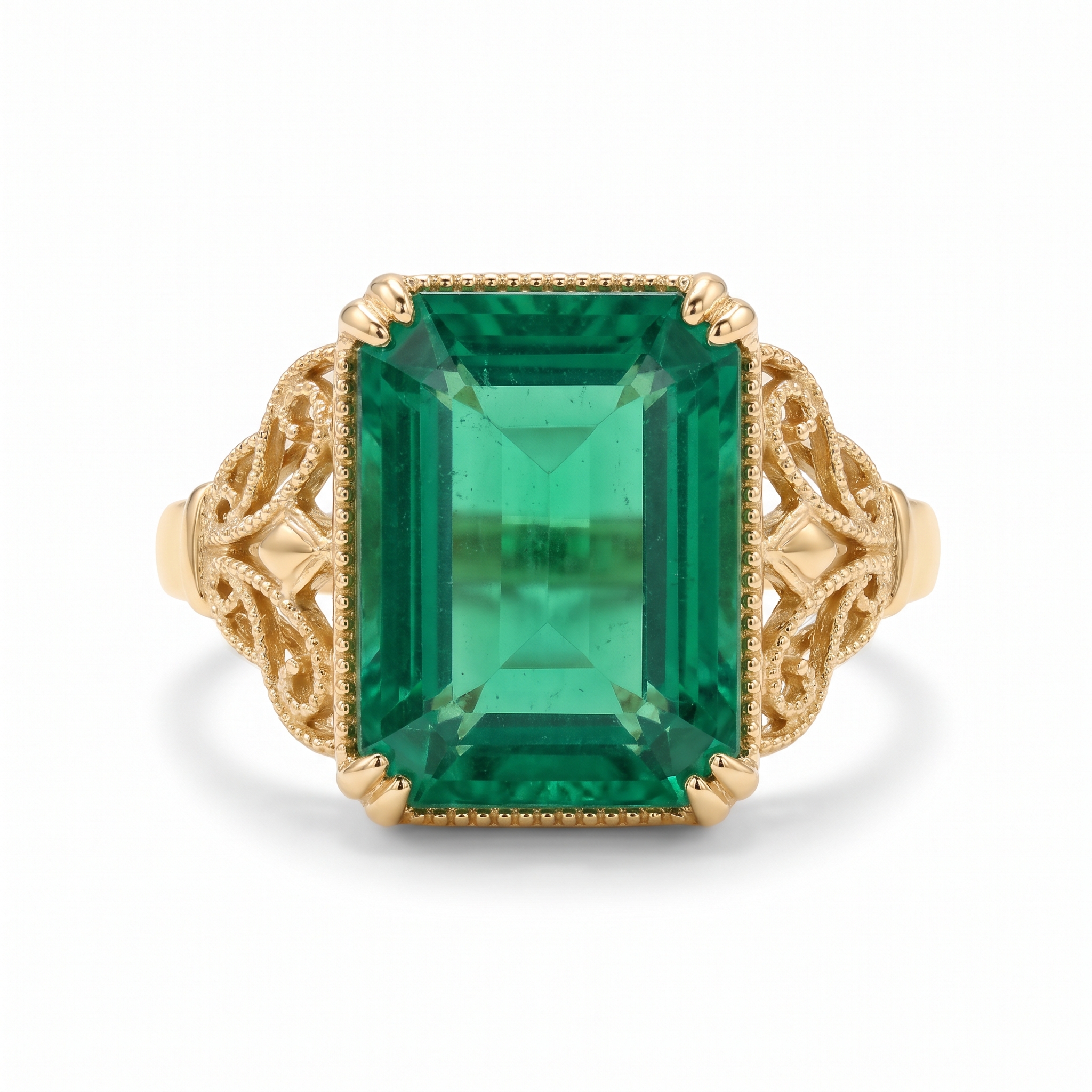 A vintage yellow gold cocktail ring holding an emerald-cut green emerald with milgrain filigree shoulders